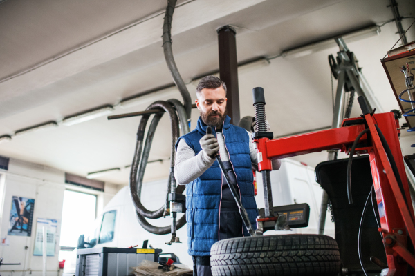 Mature man mechanic repairing a car in a garage.