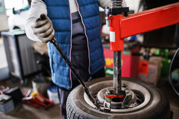 Unrcognizable man mechanic repairing a car in a garage.