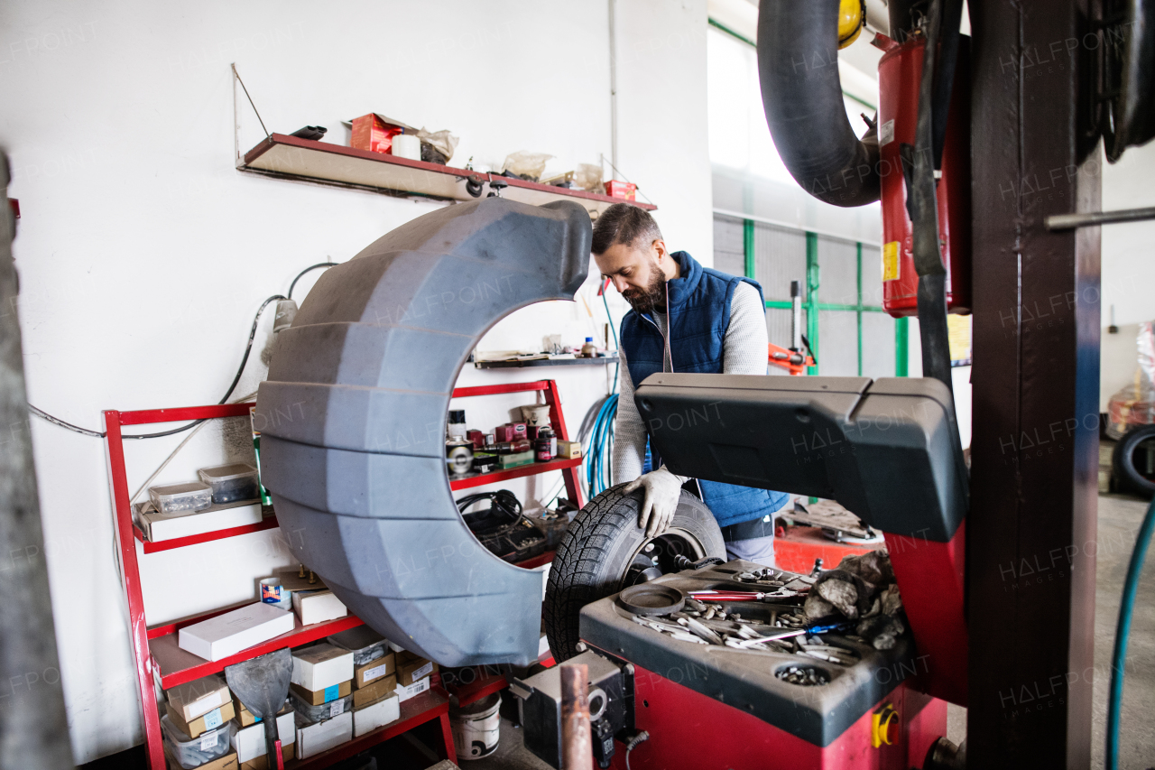 Mature man mechanic repairing a car in a garage.