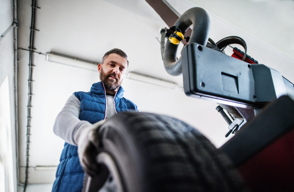 Mature man mechanic repairing a car in a garage.