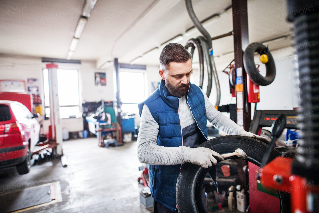 Mature man mechanic repairing a car in a garage.