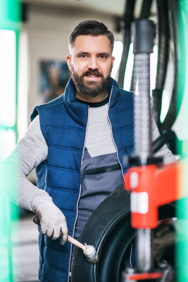 Mature man mechanic repairing a car in a garage.