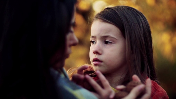 A happy young mother with a small daughter in autumn nature at sunset, talking. Slow motion.