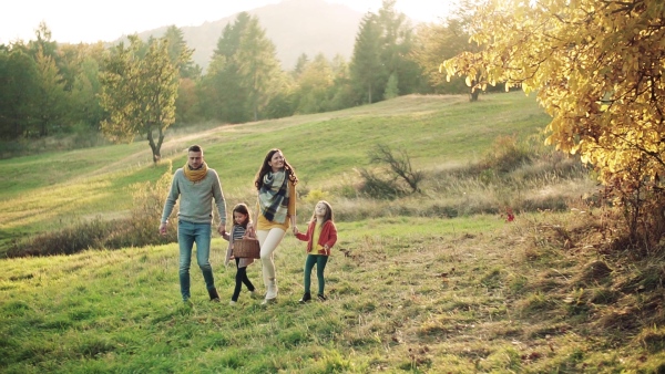 A happy young family with two small children walking in autumn nature. Slow motion.