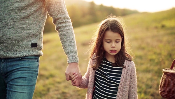 Two small girls with unrecognizable parents walking in autumn nature. Slow motion.