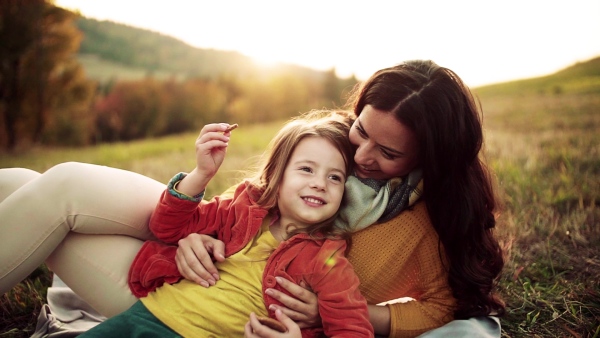 A happy young mother with a small daughter in autumn nature at sunset, eating biscuits. Slow motion.