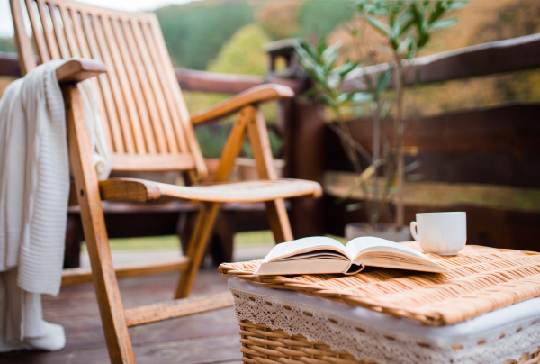 An empty wooden chair and a book on a basket on a terrace on a sunny day in autumn.