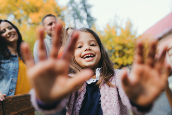 A portrait of happy young family with two small children in autumn nature, having fun.