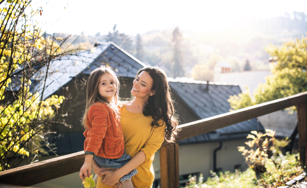 A portrait of young mother with a small daughter walking in park in autumn.