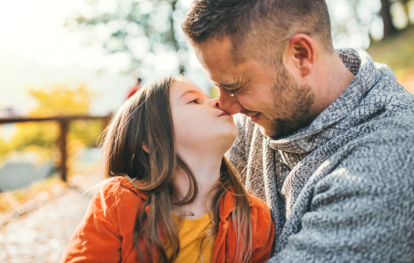 A young father holding a small daughter in autumn nature, having fun.