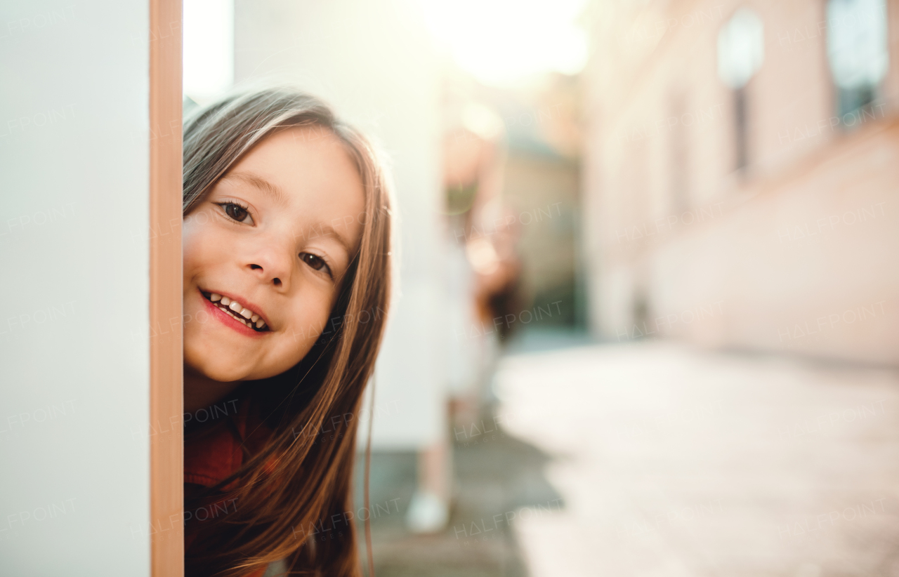 A happy small girl having fun in town in autumn, looking at camera.