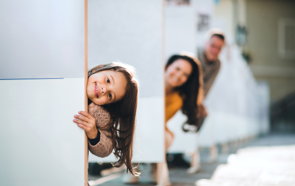 A happy small girl with her family having fun in town in autumn, family time.