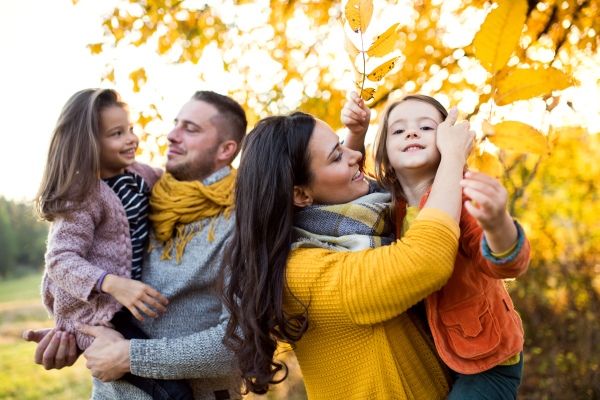 A portrait of happy young family with two small children in autumn nature.