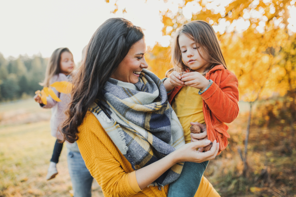 A young family with two small children standing in autumn nature.