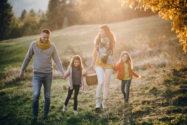 A happy young family with two small children walking in autumn nature.