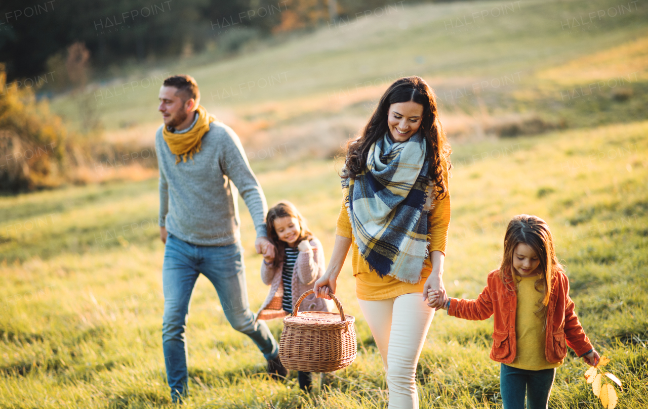 A happy young family with two small children walking in autumn nature.