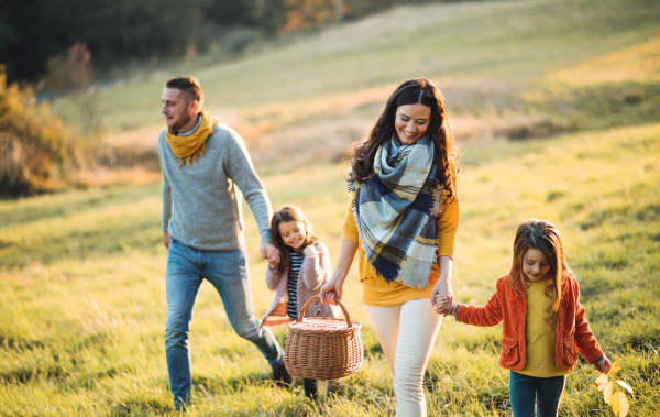 A happy young family with two small children walking in autumn nature.