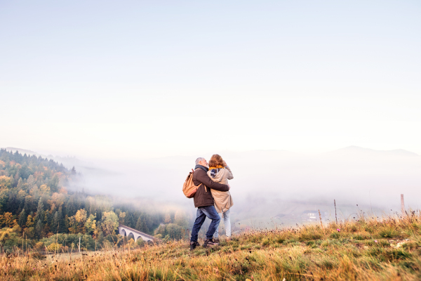 Active senior couple on a walk in a beautiful autumn nature. Rear view.