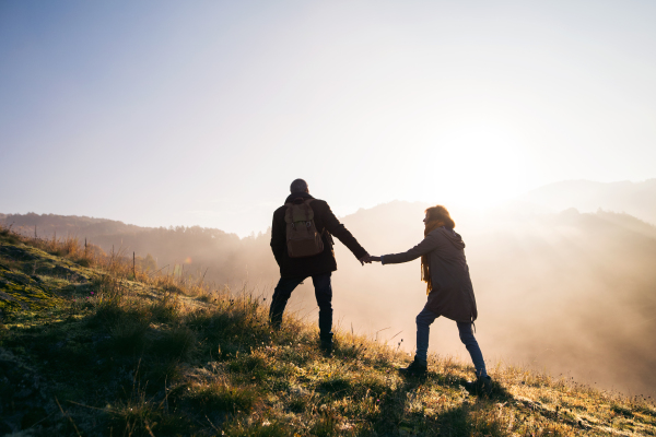 Active senior couple on a walk in a beautiful autumn nature at sunrise.