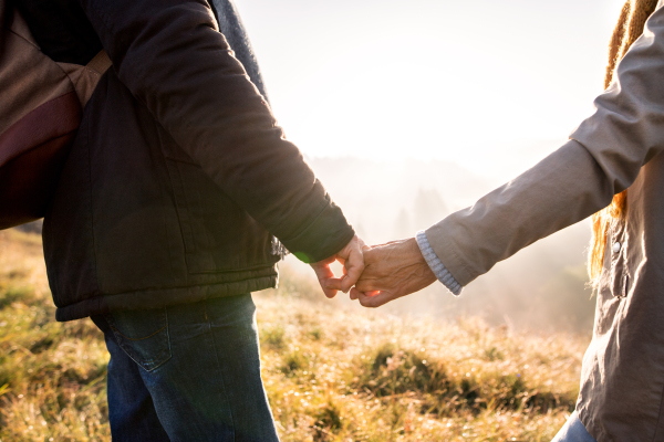 Unrecognizable active senior couple on a walk in a beautiful autumn nature.