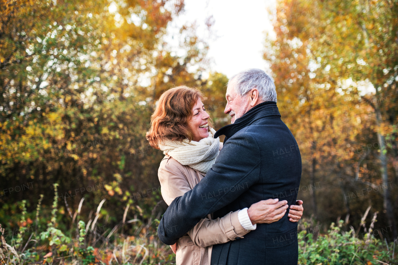 Active senior couple on a walk in a beautiful autumn nature. A man and woman looking at each other, hugging.