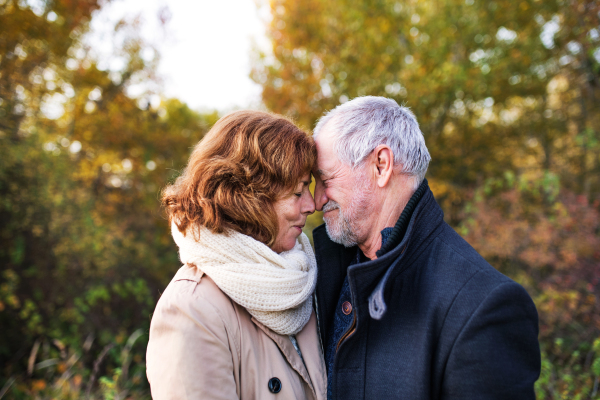 Active senior couple on a walk in a beautiful autumn nature. A man and woman in love, touching noses.