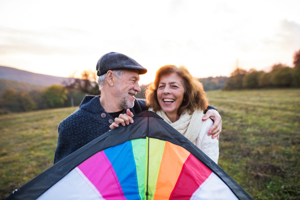 A portrait of senior man and a woman with a kite in an autumn nature.