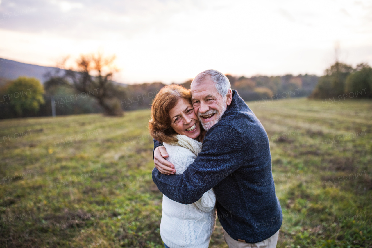 Senior couple in love on a walk in an autumn nature. Senior man and a woman hugging at sunset. Copy space.