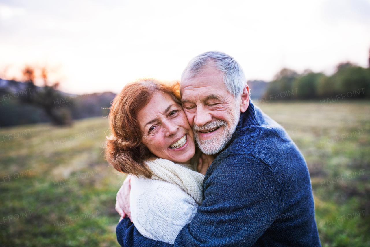 Senior couple in love on a walk in an autumn nature. Senior man and a woman hugging at sunset.