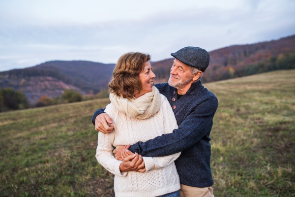 Senior couple in love on a walk in an autumn nature. Senior man and a woman hugging, looking at each other. Copy space.