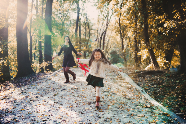 A portrait of young mother with a small daughter walking in forest in autumn nature.