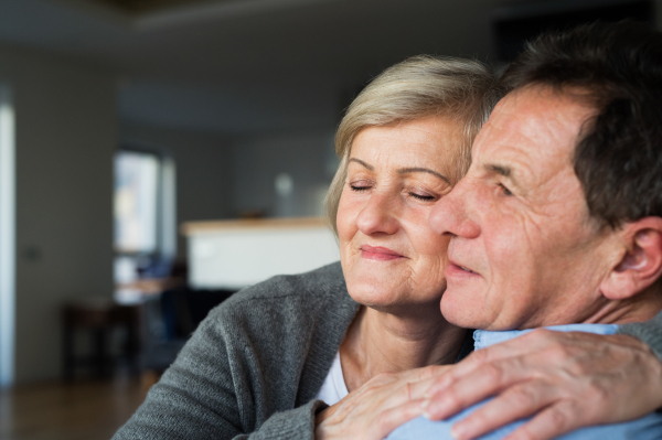 Beautiful senior woman and man in love in their living room, hugging