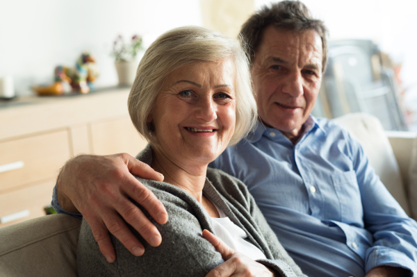 Beautiful senior woman and man sitting on a couch in living room, hugging