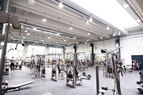 Modern gym with various exercise machines in it, people working out