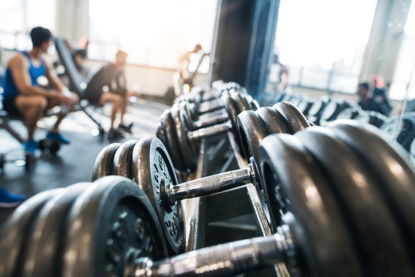 Close up of metal heavy dumbbells in holder in modern gym. Weight training equipment.