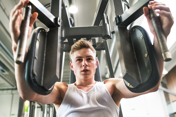 Young handsome fit man working out, using weight machine.