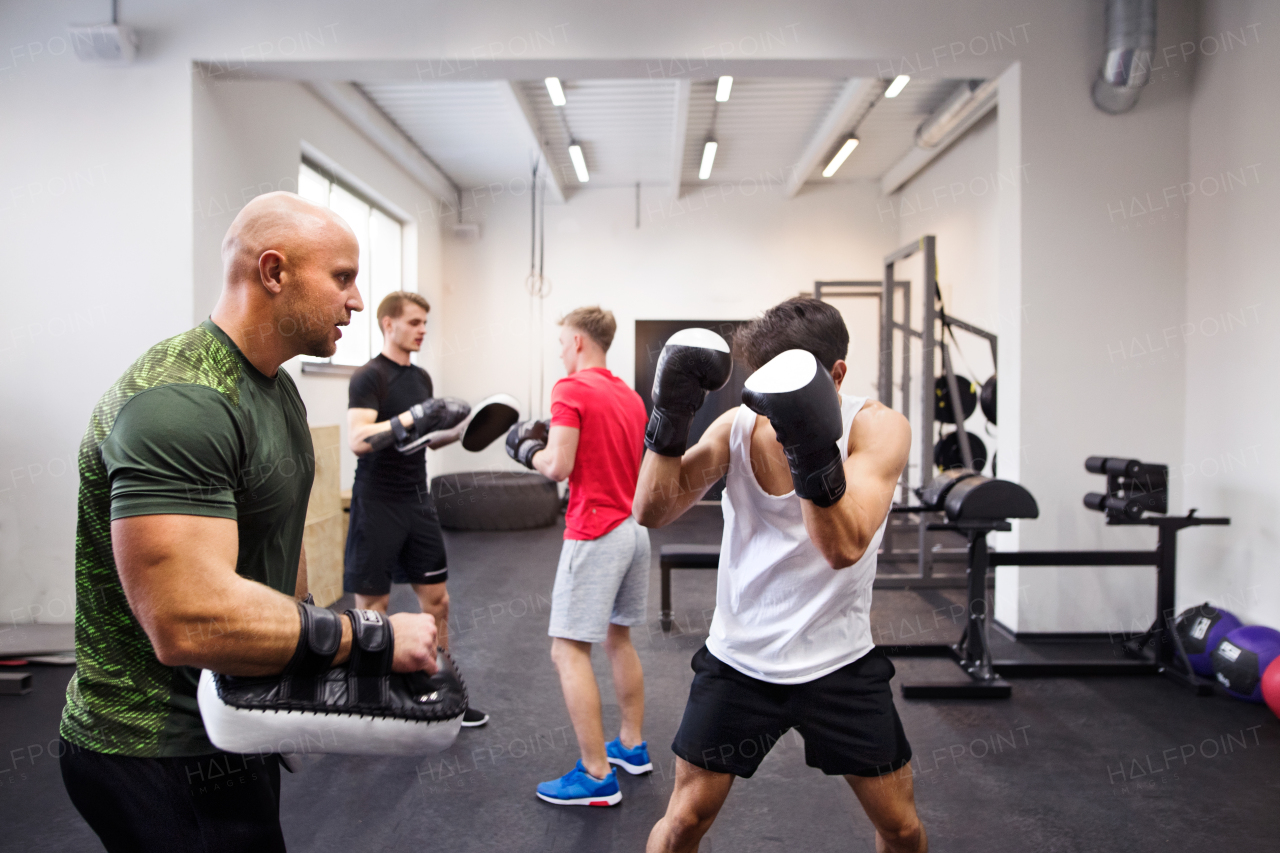 Handsome fit hispanic man boxing with his personal trainer. Athlete boxers wearing boxing gloves sparred in boxing gym.