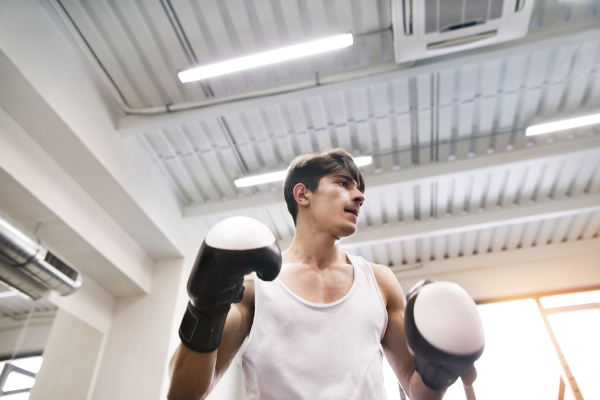 Handsome fit hispanic man in gym boxing with unrecognizable rival