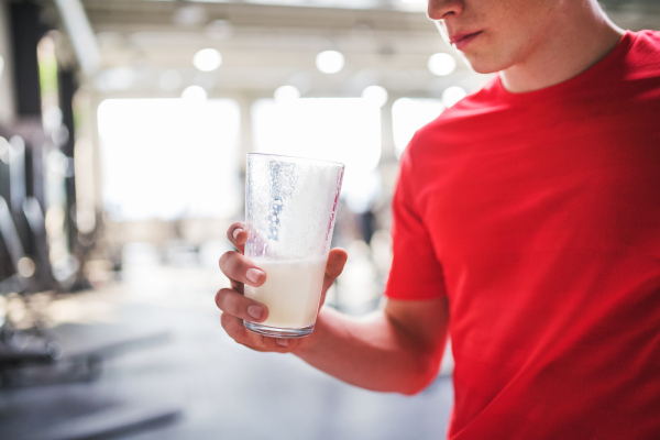 An unrecognizable young fit men in crossfit gym holding a glass with protein drink. Copy space.