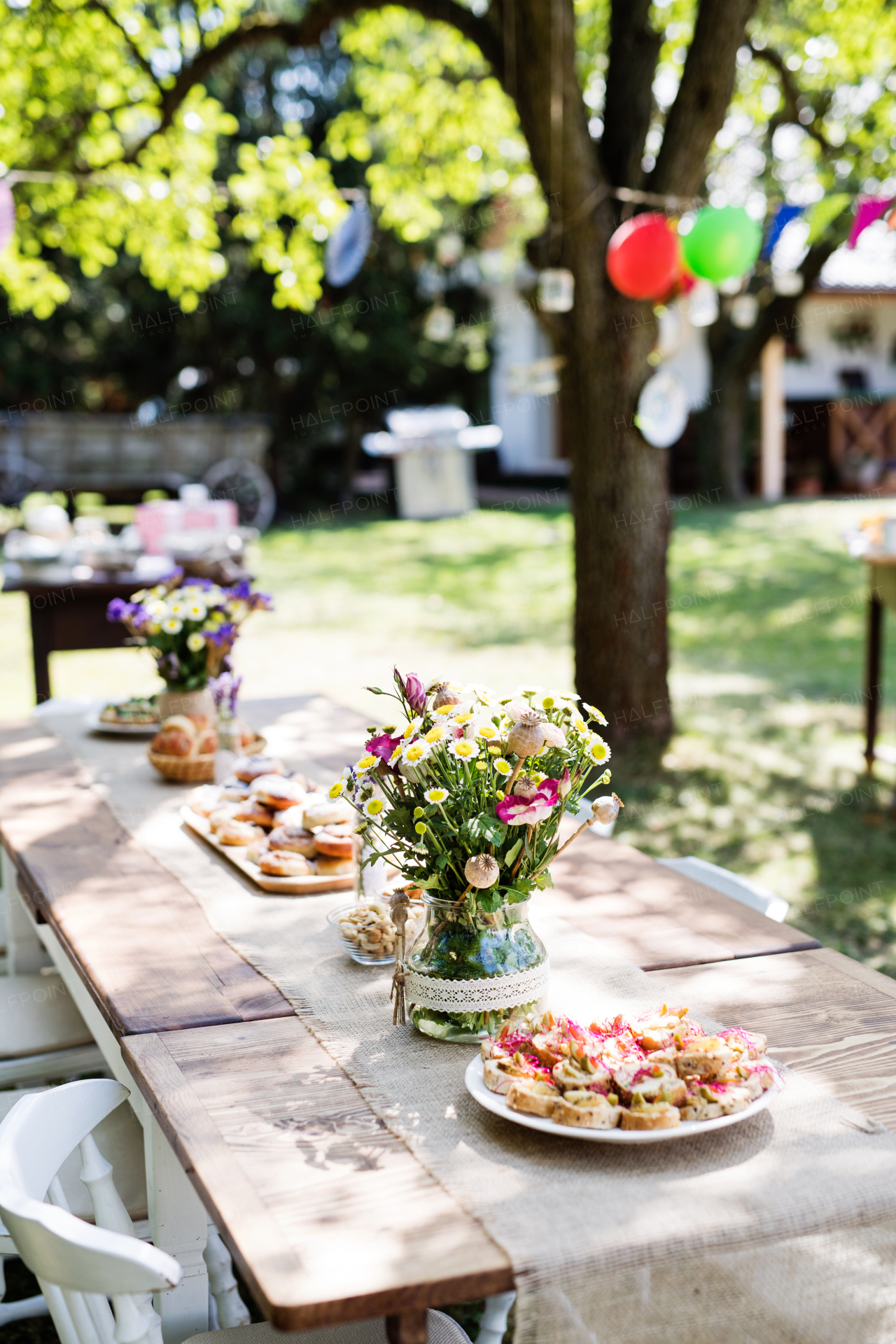 Table set for a garden party or celebration outside. Flowers and snacks on the decorated table in the garden.