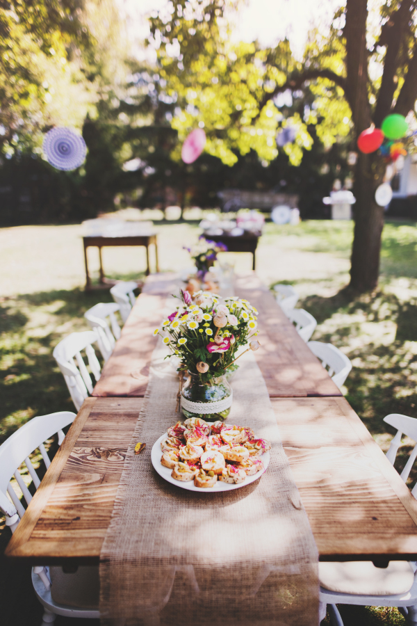 Table set for a garden party or celebration outside. Flowers and snacks on the decorated table in the garden.