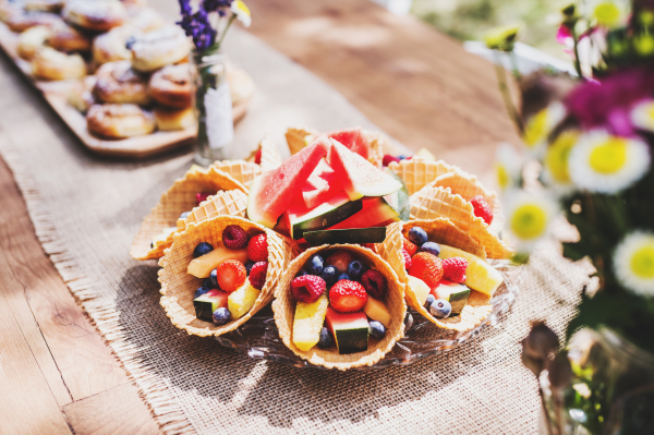 Table set for a garden party or celebration outside. Fruit snacks on the decorated table in the garden. Close up.