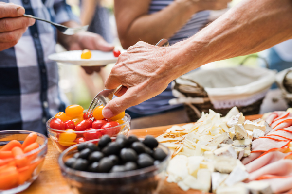 Family celebration outside in the backyard. Big garden party. Unrecognizable people eating. Close up.