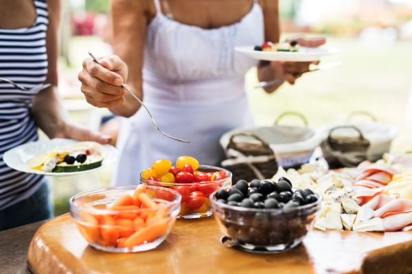 Family celebration outside in the backyard. Big garden party. Unrecognizable people eating. Close up.