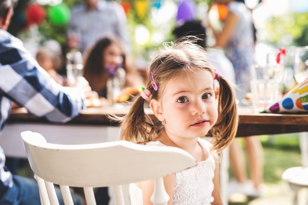 Family celebration outside in the backyard. Big garden party. Portrait of a small girl.