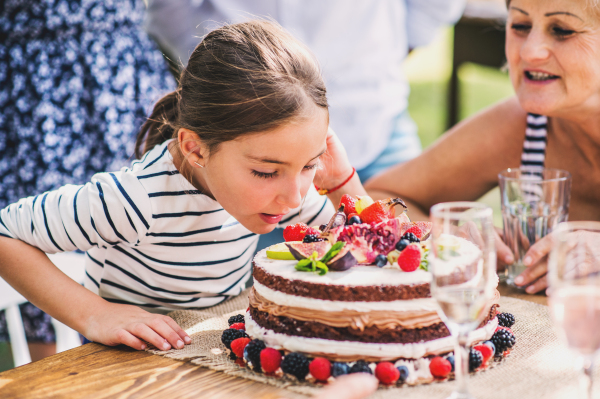 Family celebration outside in the backyard.Big garden party. Birthday party. Small girl with a birthday cake.