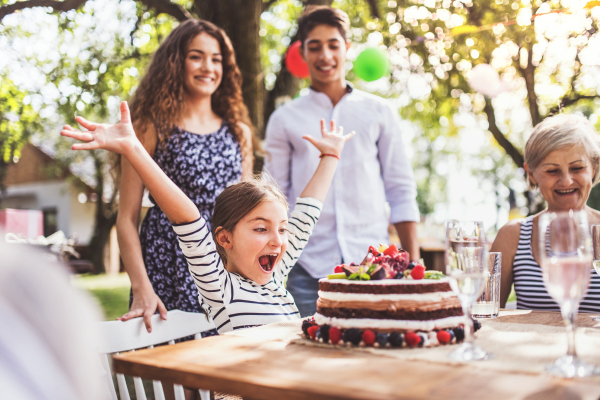 Family celebration outside in the backyard.Big garden party. Birthday party. Small girl with a birthday cake.