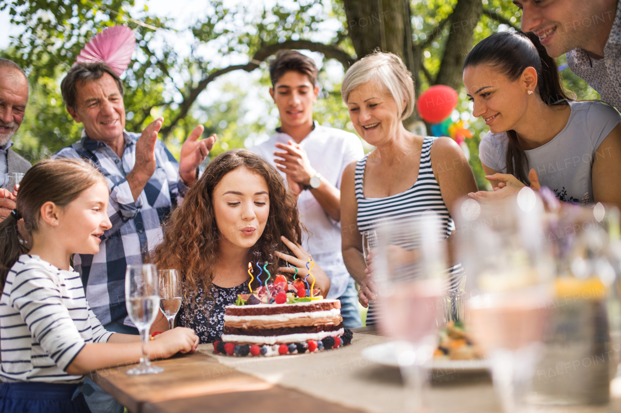 Family celebration outside in the backyard.Big garden party. Birthday party. A teenage girl with a birthday cake.