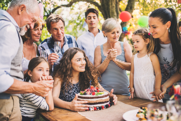 Family celebration outside in the backyard.Big garden party. Birthday party. A teenage girl with a birthday cake.