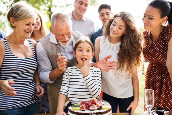 Family celebration outside in the backyard.Big garden party. Birthday party. Small girl with a birthday cake.